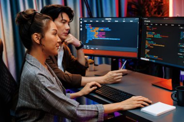 Bilgi teknolojisi geliştiricileri modern ofisteki neon ışık odasında verileri çevrimiçi olarak çalıştıran akıllı web sitesi geliştirme kodlayıcı sistemine işaret ediyorlar. İnfobahn.