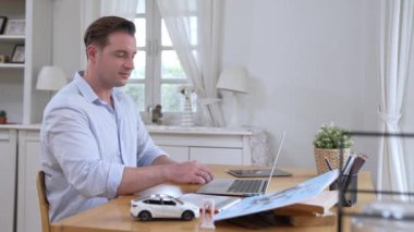 Araba tasarım mühendisi otomobil işi için otomobil prototipini ev ofisinde analiz ediyor. Otomotiv mühendisliği tasarımcısı dikkatle analiz eder, kusurları bulur ve dizüstü bilgisayarla araba tasarımında gelişmeler kaydeder.