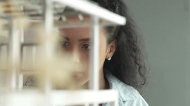 Genç İspanyol mimar mühendis ev modeli inşaatı ile karşı karşıya. Mimari model yapısını kontrol ederken proje yöneticisi binanın içine bakıyor. Yüzüne odaklan. Yönlendirici.