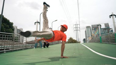 Genç mutlu hipster break dans yapar ya da arkadaşıyla birlikte hiphop müziğine taşınır. Dondurmada ve el sallamada usta bir dansçı. Modern yaşam tarzı. Açık hava müziği 2024. Yumuşak bir şekilde..