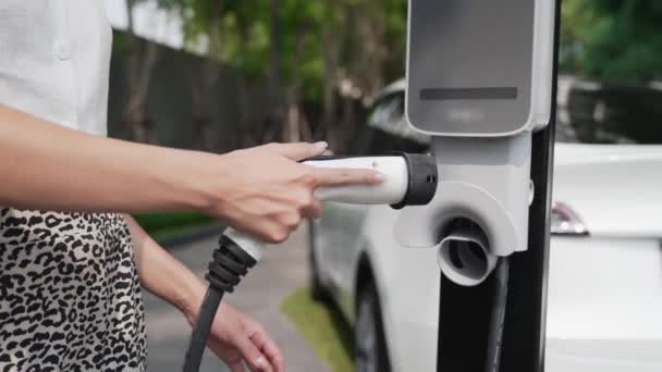 城市住宅区电动汽车充电站慢动作妇女充电电动汽车电池与电动汽车内部可持续绿色可再生能源清洁生活方式的关系 — 图库视频影像