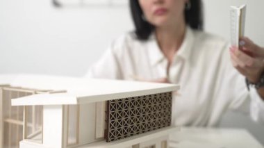 Profesyonel mühendis mimarın üçgen ölçekli ölçü evi modelini kullanarak modern ofisteki yapı uzunluğunu not alarak yakınlaşması. İş tasarımı. Tertemiz..