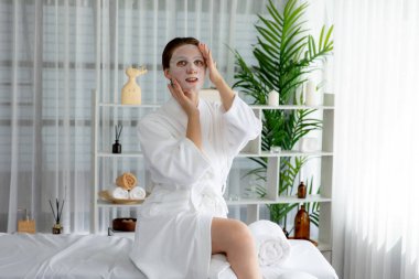 Kaplıca salonunun sakin, modern gün ışığı atmosferi, kadın müşteri poz veriyor ve yüz maskesi ile gençleştiriyor. Yüz bakımı ve güzellik kozmetolojisi prosedürü. Sessiz.