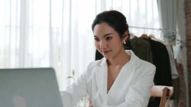 Çalışma masasında internet içeriği için dizüstü bilgisayar kullanan ya da evden çalışan genç bir iş kadını. Kıyafet ve tekstil işi pazarlama analizi. Canlılık