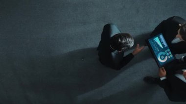 Profesyonel iş adamının yukarıdan görünüşü bir ekibe katıldı ve yönetici müdürle tokalaştı. Akıllı pazarlama ekibi tabletteki yatırım verilerini analiz etmek için birlikte çalışıyor. Müdürlük.