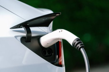 Elektrikli araç portuna bağlı EV şarj prizi kolu şarj istasyonundan şarj oluyor. Modern tasarlanmış EV araba ve daha iyi bir gelecek konsepti için temiz enerji sürdürülebilirliği. Eşzamanlama