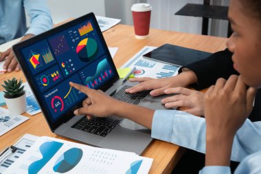 Çok ırklı analist ekibi toplantı masasındaki finansal verileri analiz etmek için BI Fintech yazılımı kullanıyor. Finansal konsol veri ekranında pazarlama göstergesi için analiz edilmiş grafikle birlikte. Uyum