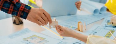 Profesyonel mühendis ve mimar, modern ofiste yeşil tasarım planı ve mimari teçhizatla toplantı masasında eko ev projesinde işbirliği yapmaktadır. Eline odaklan. Kapatın. Tanımlama.