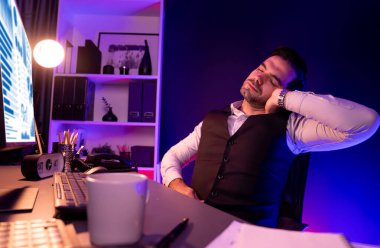 Sırtında, boynunda ve tüm vücudunda ağrıları olan zeki bir iş adamı, esneme hareketleri yapıyor. Gece geç saatlerde mor neon ışıklı odada uzun süre analiz edilen pazar verileri kavramı. Tahmin et..