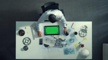 Türbin motoru veya jet motoru tasarımı ve çeşitli metal teçhizat dağılımı ile toplantı masasında yeşil ekranlı tablet üzerinde çalışırken telefona bakan mühendis görüntüsü. Hizalama.