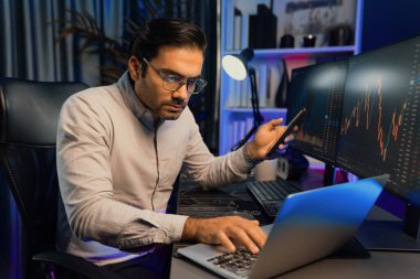 Akıllı tüccar akıllı iş adamı akıllı telefonu kullanarak modern evde kâr amaçlı finans teknolojisi ile neon ışık ofisindeki bilgisayarda dinamik borsa yatırımlarını araştırır ve analiz eder. Tahmin et..