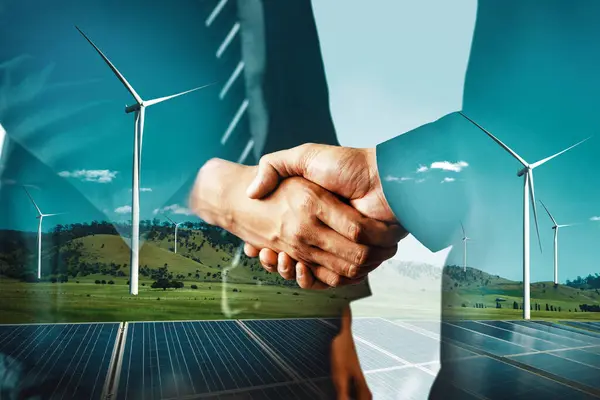 stock image Double exposure graphic of business people handshake over wind turbine farm and green renewable energy worker interface. Concept of sustainability development by alternative energy. uds