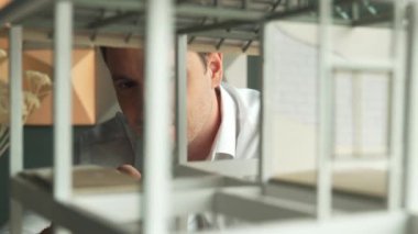 Kafkasyalı mimar mühendisinin yakın çekimi ev inşaatını denetlemek ve bina malzemelerini kontrol etmek. Proje yöneticisi modele dikkatlice bakarken kalemi işaret ediyor. Yönlendirici.