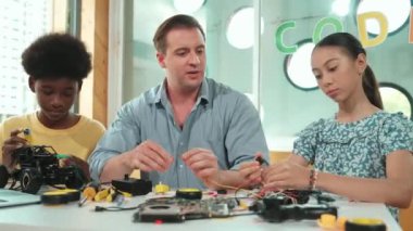 Yetenekli öğretmen Afrikalı çocuğa elektrikli aletleri açıklarken liseli kız model tamir ediyor. Çok kültürlü bir öğrenci robot araba yapımı ve elektronik aletleri öğreniyor. Öğretim