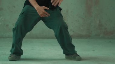 Kulaklıktan çimento arka planda müzik dinlerken break dans pratiği yapan yakışıklı bir hippi. Yakışıklı Asyalı sokak dansçısı robot dansı yapıyor. Açık hava sporu 2024. Modern dans. hiphop.