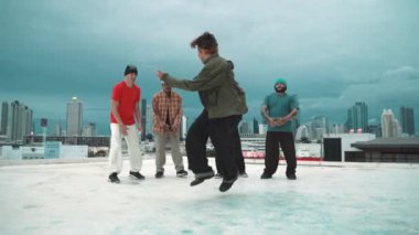 İspanyol hipster dansları şehrin mavi gökyüzü manzaralı çok kültürlü arkadaşlarıyla çevrili. Çatıda bir grup sokak dansçısı sahne alıyor. Aktif, eğlenceli, mutlu atmosfer. Açık hava sporu 2024 hiphop..