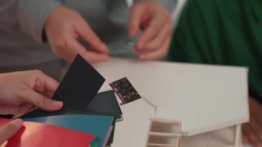 Ev tasarımcısı mimari ekipman kullanarak bir plan çizerken, iç tasarımcı da müşterilerin talebine göre renk örneklerinden uygun renkler seçiyor. Değiştirilmiş