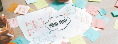 Yaratıcı bir girişim grubu beyin fırtınası fikri. Genç ve güzel iş adamları birlikte çalışıyor ve renkli yapışkan notlarla fikirleri paylaşıyorlar. Eline odaklan. Üst Manzara. Değiştirilmiş.