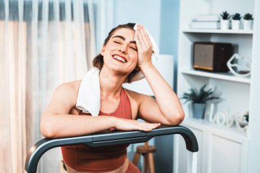 Spor ve atletik bir kadın, evdeki fiziğe ve sağlıklı spor yaşam tarzına uygun vücut egzersizi sırasında koşu bandında koşuyor. Gaiety evde egzersiz eğitimi.