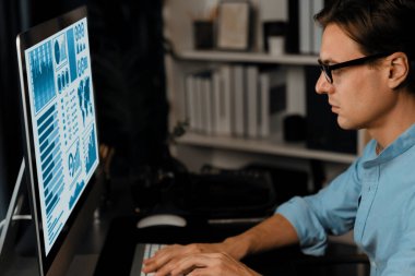 Akıllı iş adamı iş paragrafı dinamik pazarlama analizi planını analiz ediyor. Kağıt kağıtları ve bilgisayar monitörü raporlarını gece evdeki belge verileriyle karşılaştırmak için hazırlıyor. Bireysel.