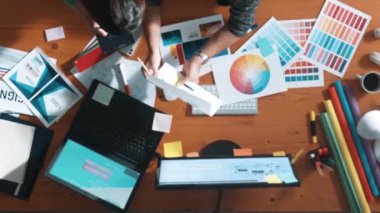 Akıllı tasarımcının renkli paletlerden renk seçmesine yardım ederken yukarıdan aşağı görünümü. Dizüstü bilgisayardan logoya bakarken birlikte çalışan ve planlayan iş adamlarının hava görüntüsü. Sempozyum.