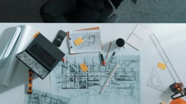 Gevşemiş akıllı inşaat mühendisinin en iyi görüntüsü mola zamanında planlarla birlikte masada uzanıyor. Dizüstü bilgisayar ve ekipman üzerinde çalıştıktan sonra uyuyan mühendisin hava görüntüsü. Hizalama.