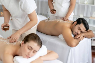 Lüks spa salonlarında sıcak mum ışığında cilt bakımı gören mutlu çift müşterisi. Sağlık kaplıcasında güzellik tedavisiyle tuz temizliği. Sessiz.