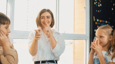 Güzel öğretmen, buruna dokunan öğrencilere vücut organlarını öğretir. Çeşitli çocuklar etkinlik yapıyor ve sınıfta öğretmenlerle oynuyorlar. Çocuk öğrenimi, uluslararası okulda okumak. Etkinlik.