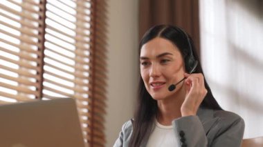 Kadın çağrı merkezi operatörü ya da müşteri hizmetleri çalışanı, müşteriye yardım etmek için kulaklıkla konuşurken çalışma alanı üzerinde çalışıyor. Profesyonel modern iş hizmeti. Blithe