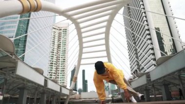 Asyalı hippi break dans çalışmasının düşük açılı kamerası ya da kulaklık takarken break dans performansı. Serbest dans, break dans, sokak dansı. Neşeli bir ruh hali. Açık hava sporu 2024. Yumuşak bir şekilde..