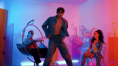 Çok kültürlü bir arkadaş kürsüde otururken Asyalı yetenekli bir dansçı modern müziğe geçiyor. Profesyonel dansçı, hipster takımı tezahürat yaparken ve desteklerken enerjik adımlar atıyor. Mutluluk.