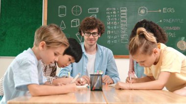 Zeki öğretmen, çeşitli çocuklar sınıf çalışması yapmak için birlikte çalışırken farklı çocukların zihin haritası çizdiği fikri açıklıyor. Çekici eğitmen öğretmek ve çalışmak hakkında konuşmak. Pedagoji.