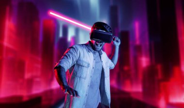 Lazer kılıcı tutan ve VR gözlük takan oyuncu. Beyaz adam, neon şatonun etrafında dikilirken görsel gerçeklik kulaklığı kullanıyor. Yenilik teknolojisi. Sapma.
