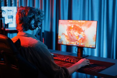 Savaş arenasında çoklu oyunlar takımıyla Moba 'da savaşan genç oyun flamasının sunucu kanalı, neon dijital ışık modern odasındaki arka görüntü ile bilgisayar monitöründe kulaklık takıyor. Toplayıcı.