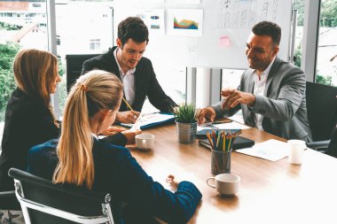 İş adamı yönetici, diğer iş adamları ve iş kadınlarıyla modern ofiste kahve fincanları ve belgelerle grup toplantısı yapıyor. Şirket çalışanlarının ortak çalışma konsepti. uds