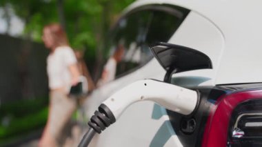 Yavaş çekim odaklı EV elektrikli araba yeşil sürdürülebilir şehir açık hava bahçesinde şarj çift bulanık arka planı şehir elektrikli araç iç organları için temiz şarj edilebilir