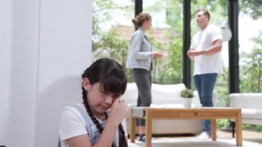 Stresli ve mutsuz genç kız köşeye kıvrılıp kulaklarını kapatarak arka planda ebeveyninin tartışmasını engelliyor. Evde aile içi şiddet ve travmatik çocukluk depresyona dönüşür. Titiz