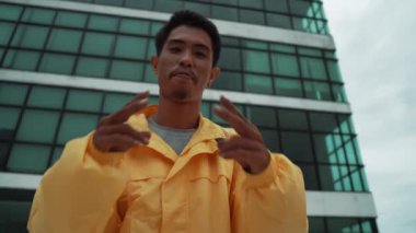 Asyalı dansçıyla dikilirken kameraya poz veren İspanyol sokak dansçısı. Çekici bir hippi, ellerini çatıdaki hip hop müziğine doğru hareket ettiriyor. Açık hava sporu 2024 hiphop..