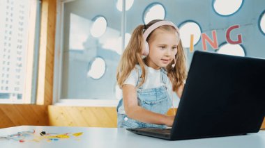 Dizüstü bilgisayarda çalışan ya da online sınıfta okuyan genç bir öğrenci. Ev ödevi yaparken ya da müzik dinlerken bilgisayarda yazan beyaz bir kız. Kulaklık takan küçük bir çocuk. Yaratıcı öğrenme. Etkinlik.