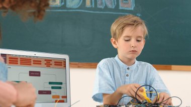 Kafkas akıllı çocuk kök teknoloji dersinde tornavida kullanarak ana tahtayı tamir ederken aynı zamanda gülümseyen öğrenci de dizüstü bilgisayar ekranı kodlu elektronik makineyi incelemek için birlikte çalışıyor. Pedagoji.