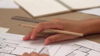 Akıllı mimar ya da akıllı mühendisin ölçüm aracı ve kalem el kullanarak mimari ofisindeki inşaat isabet planı üzerine detaylı bir yazı yazışının videosu. Eline odaklan. - Yakın çekim. Tanımlama.