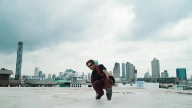 B-boy dans gösterisi profesyonel sokak dansçısı çatıda gökyüzü dövüşçüsüyle, şehir manzaralı. Çekici Asyalı hippi gösterisi, hareketli adımlar. Açık hava sporu 2024. Hip-hop tarzı. hiphop.