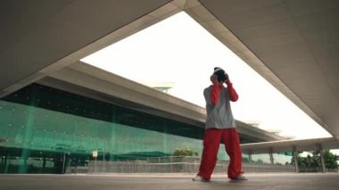 Asyalı yakışıklı hipster binada hip hop dinlerken enerjik bir dans sergiliyor. Profesyonel sokak dansçısı enerjik performansını çalışırken müziğe yöneldi. Açık hava sporu 2024. Yumuşak bir şekilde..