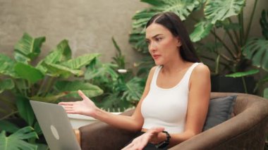 Stresli kadın, yeşillik arka planında internet üzerinden çalışırken yorgun ve hayal kırıklığına uğramış hissediyor. Bunaltıcı ve zorlu uzak çalışma görevleri. Blithe