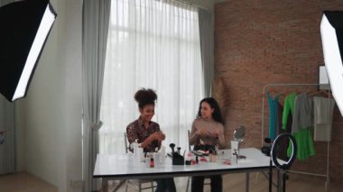 İki kadın nüfuzlu kişi canlı yayında video görüntülerini çekiyor. Makyaj çok önemli sosyal medya veya blog. Kozmetik stüdyosu ışıklandırmalı mutlu genç kız çevrimiçi pazarlama oturumu yayını için..