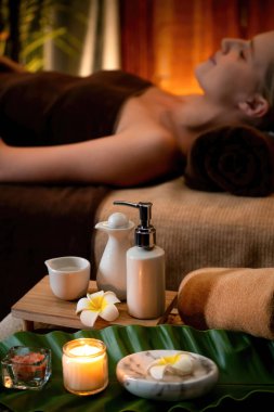Aromaterapi masajı ambiyansı ya da spa salonu kompozisyon düzeneği bulanık kadınlara odaklı dekor mumları ve spa aksesuarları ile tatil köyü veya otel arka planında keyifli aroma spa masajı yapan. Sessiz.