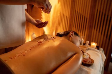 Lüks spa salonlarında sıcak mum ışığında cilt bakımı yaptıran kadın müşteri. Sağlık Spa vücut fırçasında tuz temizleme güzellik tedavisi. Sessiz.