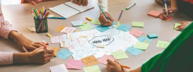 Profesyonel başlangıç grubu zihin haritası kullanarak yaratıcı pazarlama fikrini paylaşıyor. Genç yetenekli iş adamları yapışkan notlar yazarken beyin fırtınası planı yapıyorlar. Eline odaklan. - Yakın çekim. Değiştirilmiş.