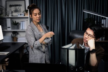 İş kadını, veri analizine işaret ederek, stresli iş arkadaşlarıyla birlikte gece geç saatlerde modern ofisteki fazla mesai şirketinde çalışmaya devam etmek için, çok çalışan proje işi klasörü evraklarına işaret ediyor. İnfobahn.