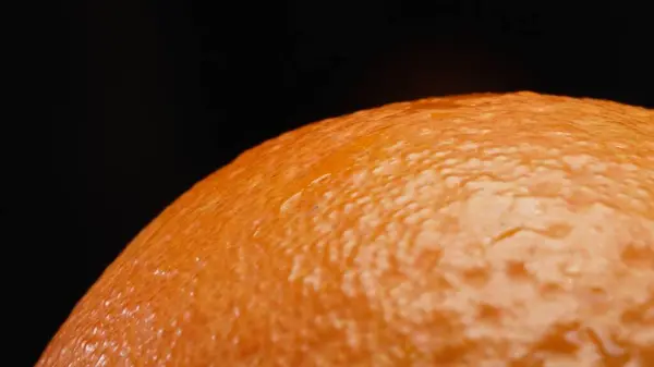 stock image Macrography, the intricate texture of an orange against a striking black background steals the spotlight. Close-up shot captures the unique patterns and details of the oranges surface. Comestible.
